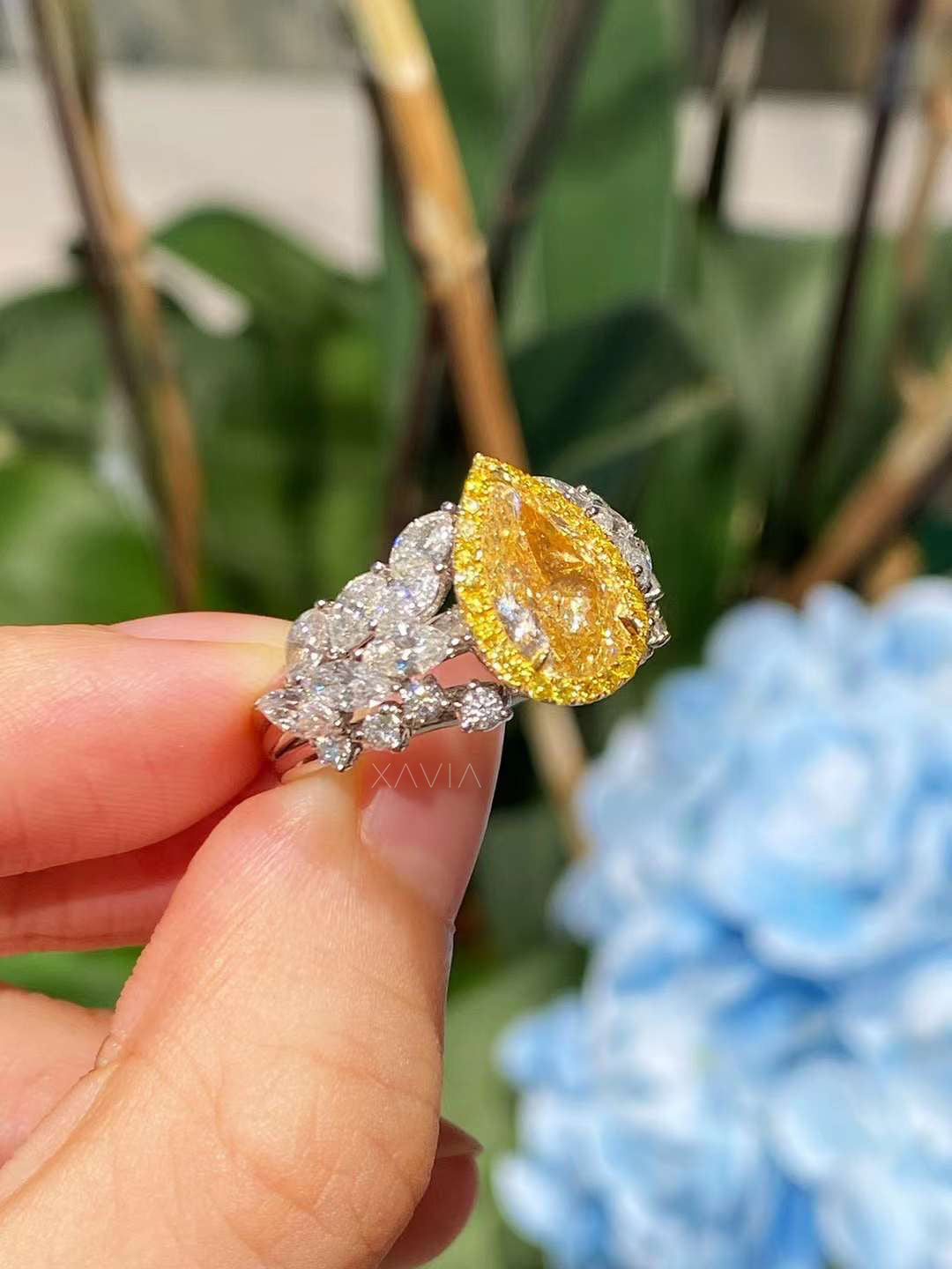 side profile of fancy yellow pear cut diamond engagement ring with halo, accented by marquise and round diamonds in leaf motif band